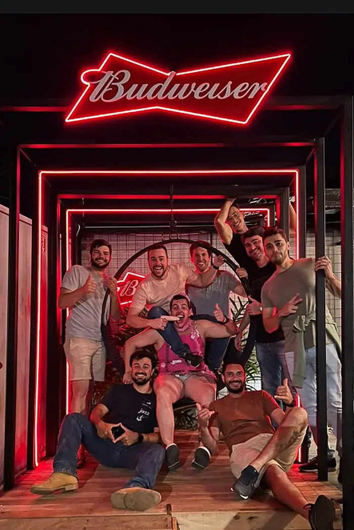 Grupo de amigos na área instagramável com neon da Budweiser